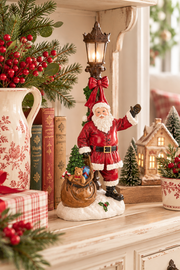 Babbo Natale Nuvole di Stoffa in resina con lampione LED, sacco di regali, alberello e base innevata, altezza 38 cm.