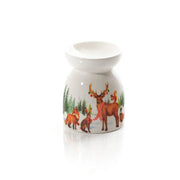 Bruciatore essenze natalizio Langs in ceramica bianca con cervi e animali del bosco, ambientato su mobile rustico in stile cottage con decorazioni natalizie.