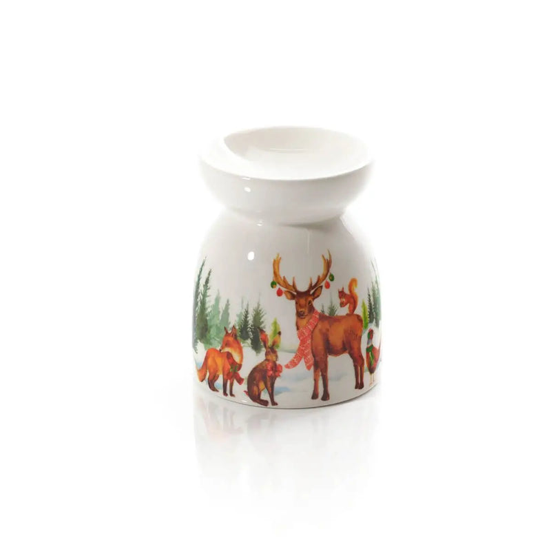 Bruciatore essenze natalizio Langs in ceramica bianca con cervi e animali del bosco, ambientato su mobile rustico in stile cottage con decorazioni natalizie.