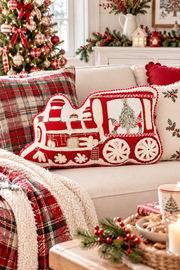 Cuscino natalizio a forma di trenino rosso e bianco ricamato su divano in stile cottage inglese.