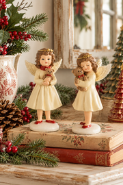 Due angioletti natalizi in resina Dekoratief alti 18 cm, con abiti color crema e orsetti, ambientati su credenza in stile cottage natalizio.