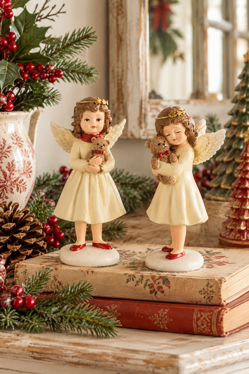Due angioletti natalizi in resina Dekoratief alti 18 cm, con abiti color crema e orsetti, ambientati su credenza in stile cottage natalizio.